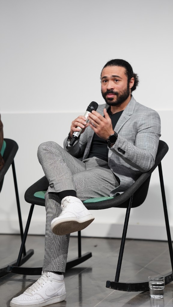 Aly Metwaly on a panel at the Sustainability MENA Hackathon, seated with a microphone in a gray suit